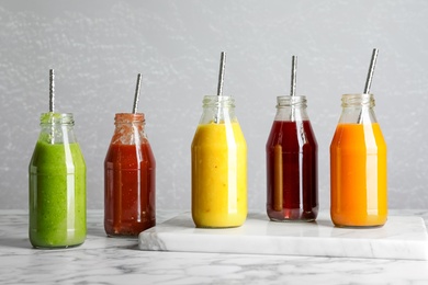 Bottles of delicious juices on white marble table