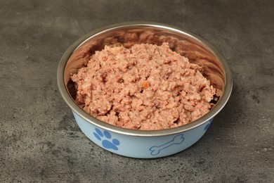 Photo of Wet pet food in feeding bowl on grey stone background