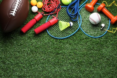 Set of different colorful sports equipment on grass, flat lay, space for text