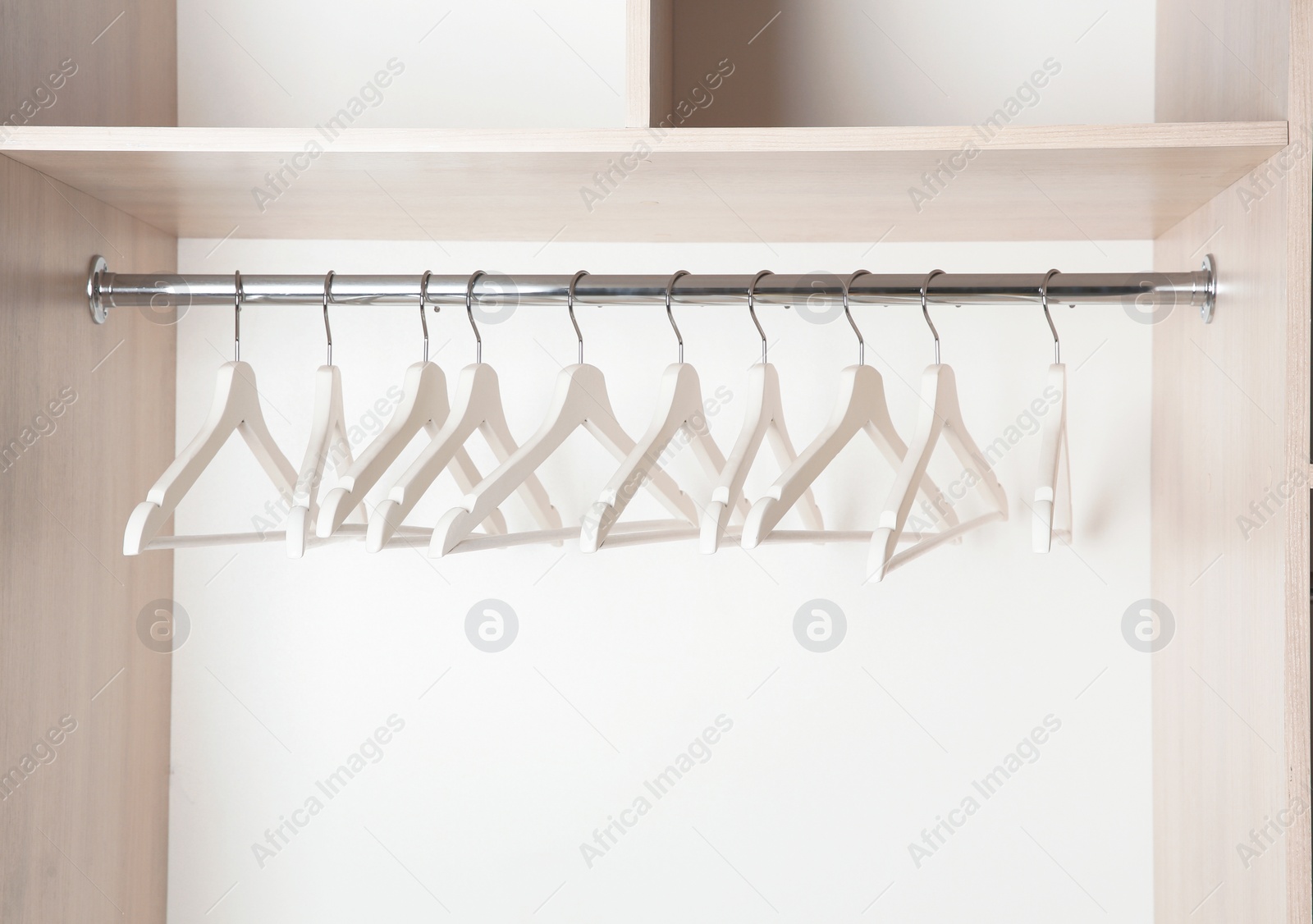 Photo of Clothes rail with wooden hangers in wardrobe