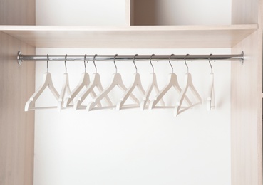 Clothes rail with wooden hangers in wardrobe