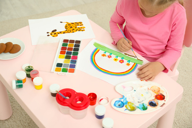 Cute little child painting at table in room