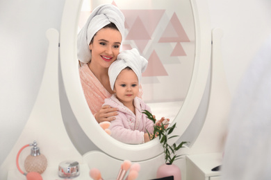 Photo of Young mother and little daughter at dressing table