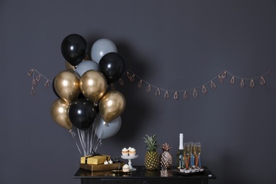 Party treats and items on table in room decorated with balloons