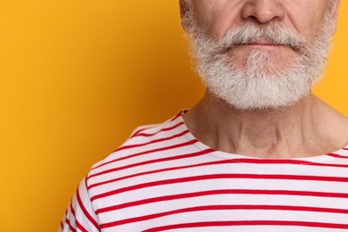 Man with mustache on orange background, closeup