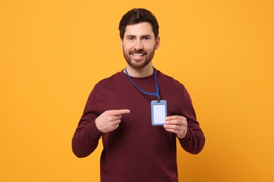 Photo of Smiling man showing VIP pass badge on orange background