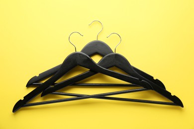 Photo of Black hangers on yellow background, top view