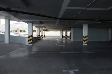 Photo of Empty open car parking garage with warning stripes on columns