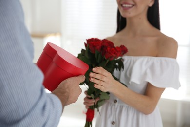 Man presenting gift to his beloved woman at home, closeup. Valentine's day celebration