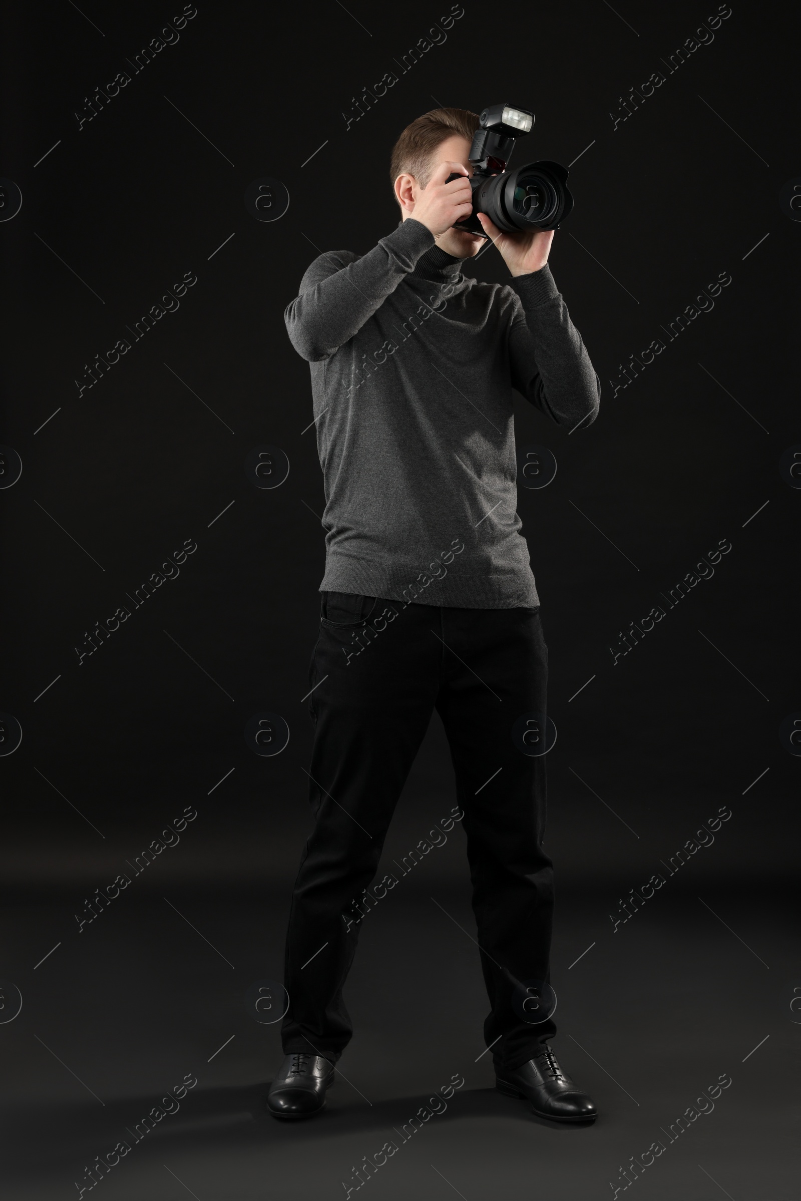 Photo of Professional photographer taking picture on black background