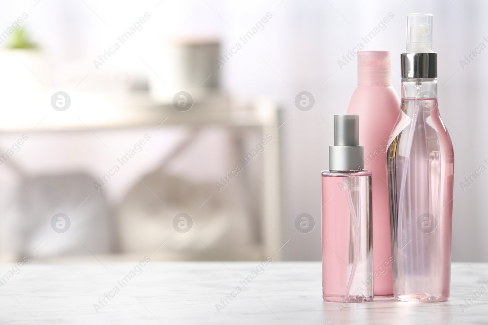 Photo of Bottles with hair care cosmetics on table in bathroom, space for text