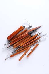 Photo of Set of different clay crafting tools on white textured table, flat lay