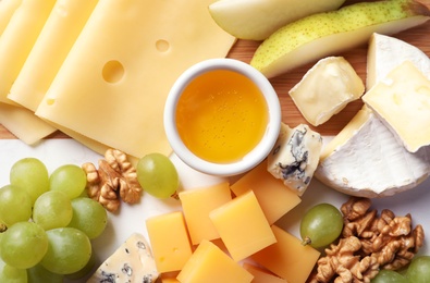 Photo of Different kinds of tasty cheese and snacks on wooden background, closeup