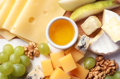 Different kinds of tasty cheese and snacks on wooden background, closeup