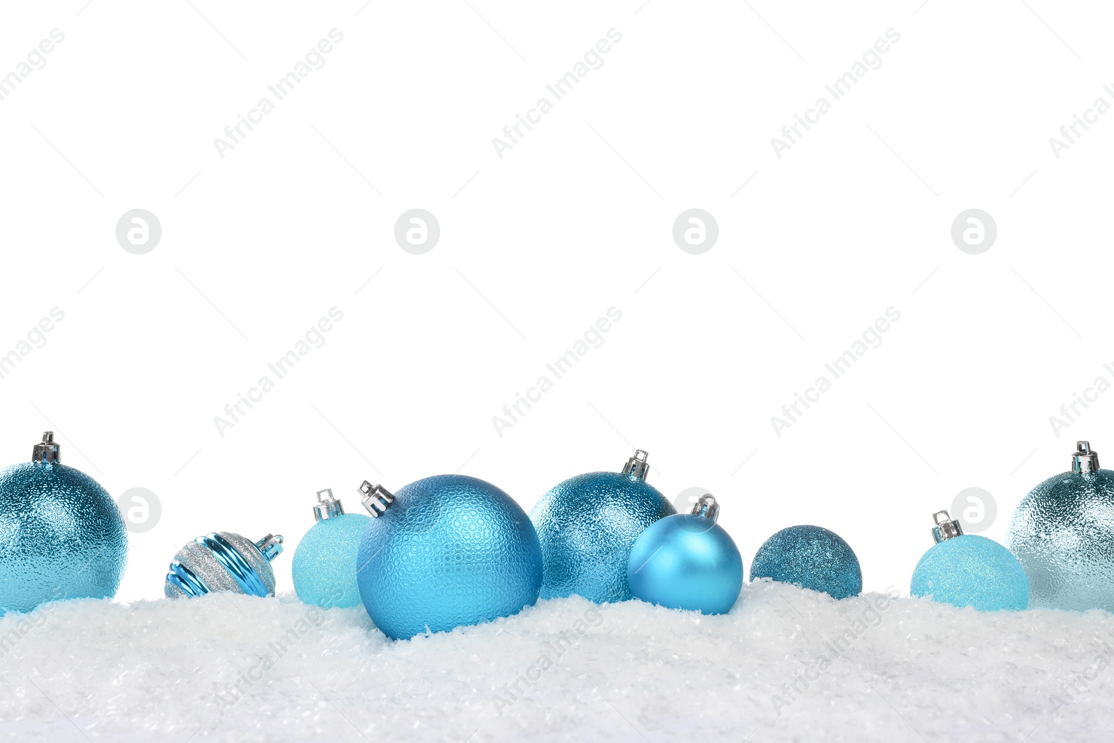 Photo of Beautiful light blue Christmas balls on snow against white background