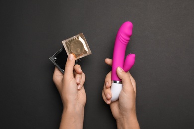 Photo of Woman with vibrator and condoms on black background, top view. Sex game