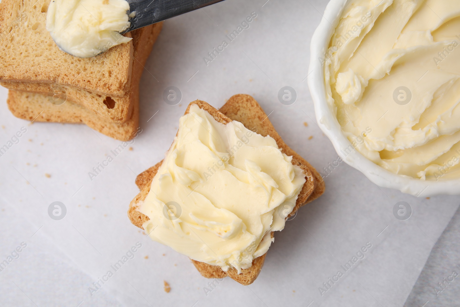 Photo of Slices of bread with tasty butter on light table, flat lay