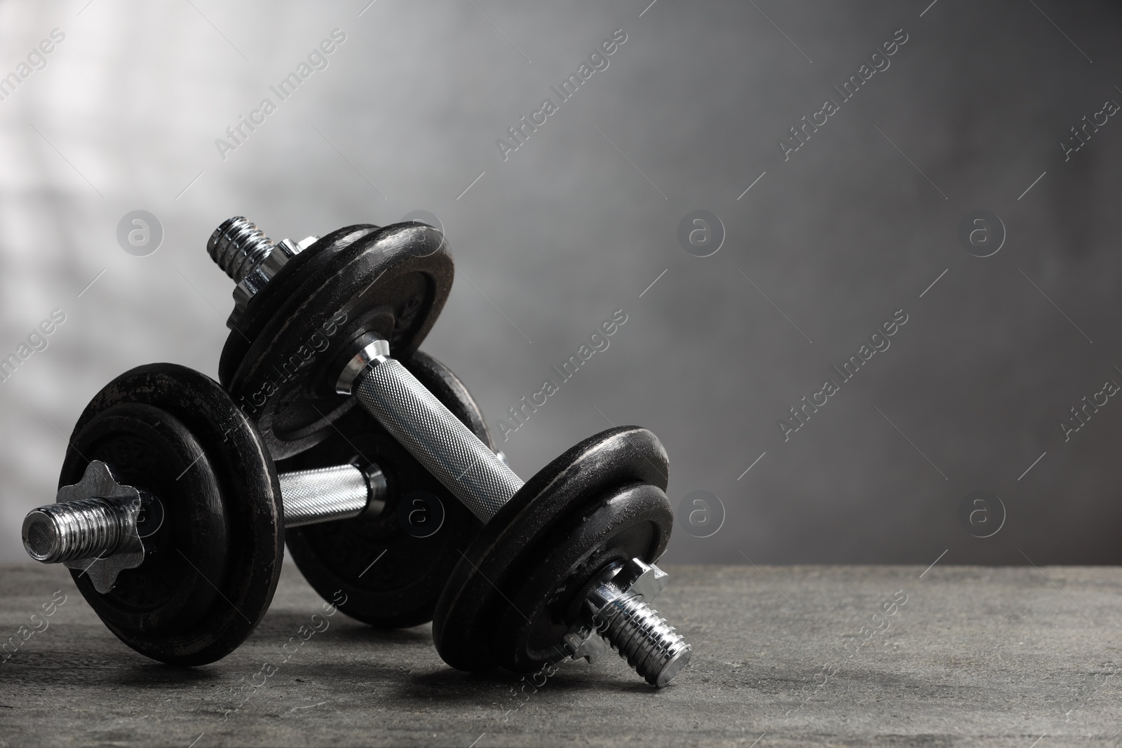 Photo of Two barbells on grey textured table, closeup. Space for text