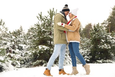 Beautiful happy couple in snowy forest on winter day