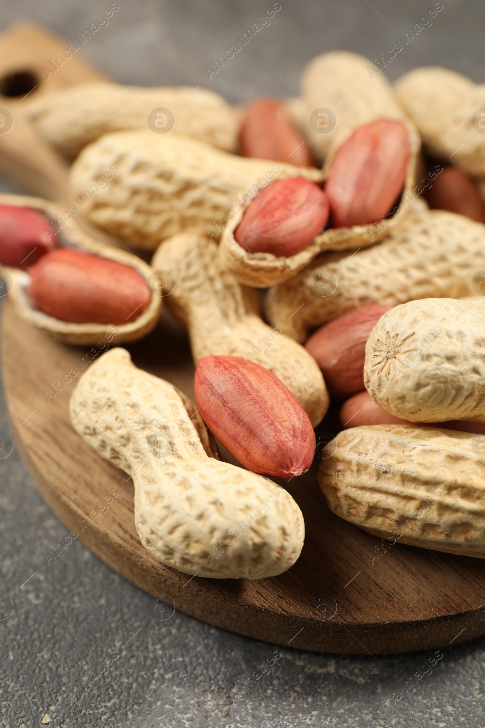 Photo of Fresh unpeeled peanuts on grey table, closeup