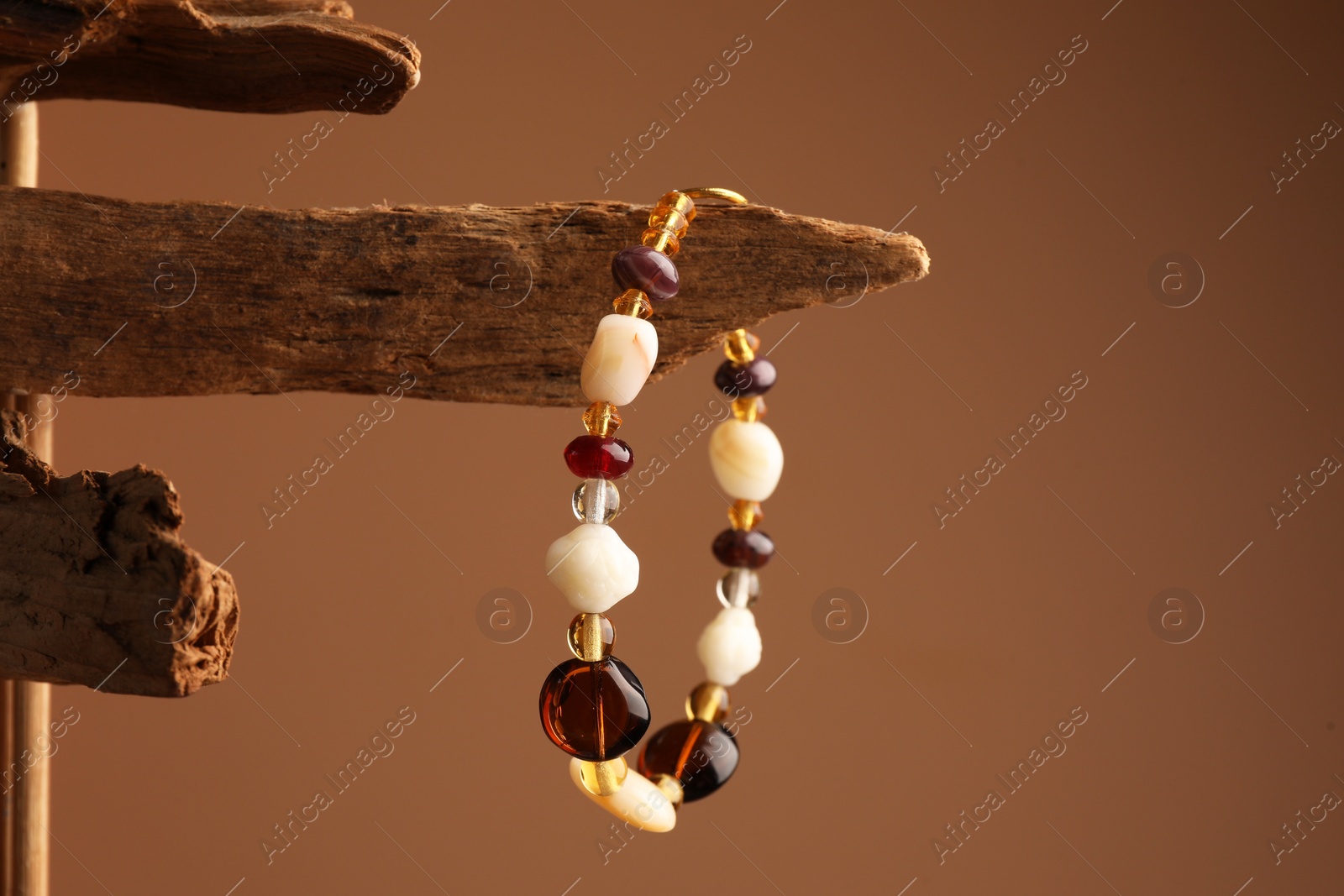 Photo of Stylish presentation of beautiful bracelet with gemstones on brown background, space for text