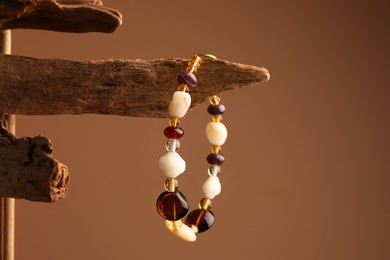Photo of Stylish presentation of beautiful bracelet with gemstones on brown background, space for text