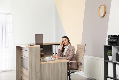 Portrait of receptionist working at desk in modern hotel