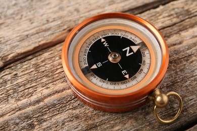 Photo of One compass on wooden table, closeup. Tourist equipment