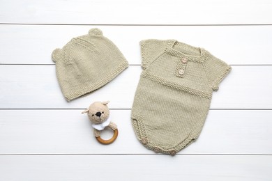 Flat lay composition with child's clothes and toy on white wooden table