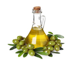 Photo of Glass jug of cooking oil, ripe olives and green leaves isolated on white