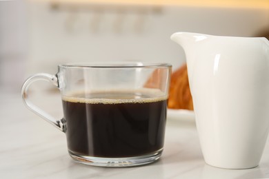 Photo of Aromatic coffee in glass cup and pitcher on white marble table