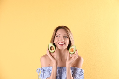 Portrait of young beautiful woman with ripe delicious avocado on color background