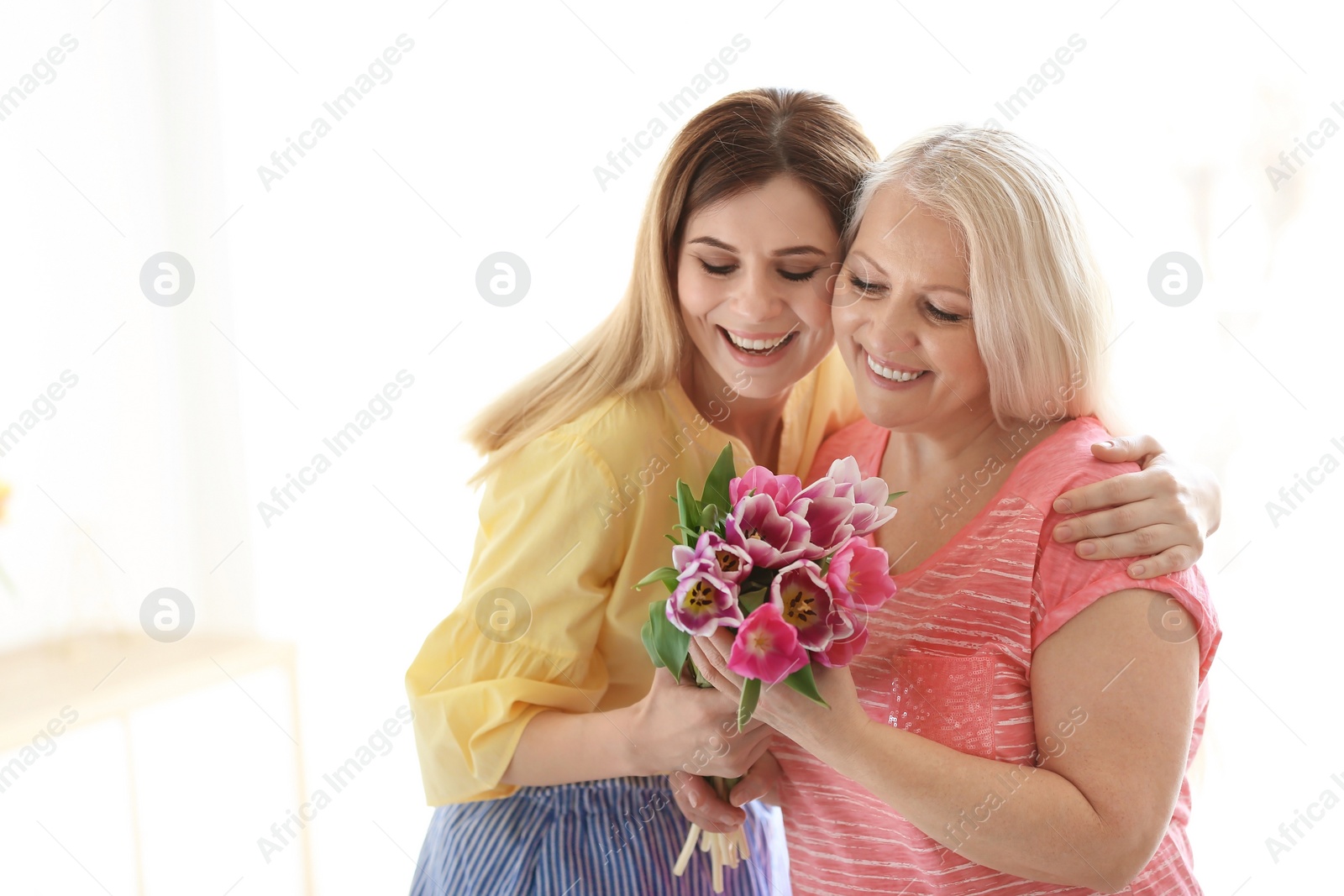 Photo of Daughter congratulating happy mature woman on Mother's Day at home