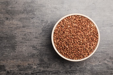 Photo of Buckwheat grains on grey table, top view. Space for text