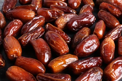 Photo of Many sweet dried dates on dark grey background, closeup