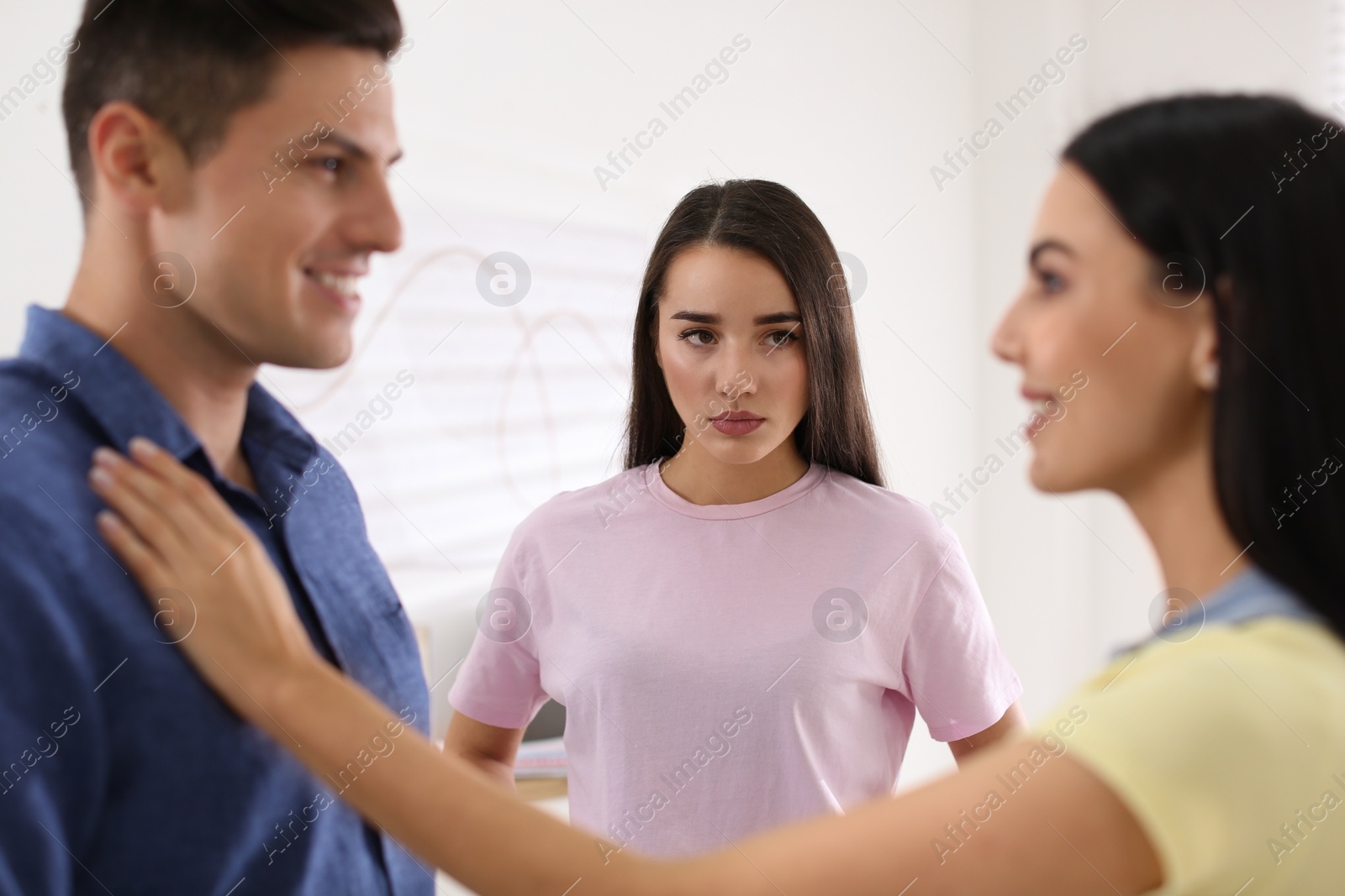 Photo of Unhappy woman feeling jealous while couple spending time together indoors