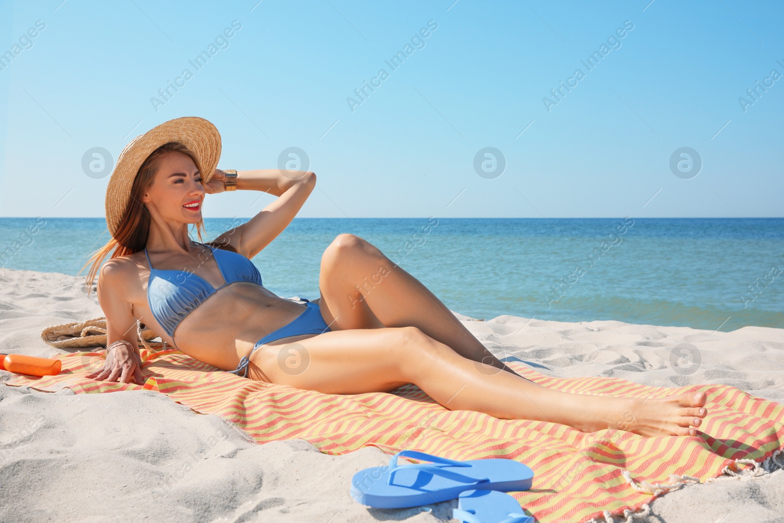 Photo of Woman with towel and other beach stuff on sand near sea