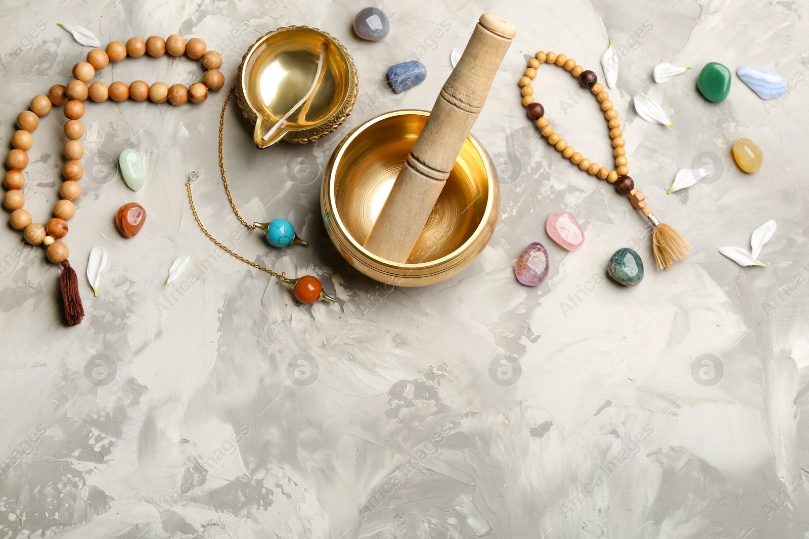 Photo of Flat lay composition with golden singing bowl on grey table, space for text. Sound healing