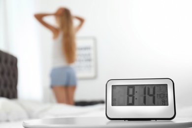 Photo of Digital alarm clock and blurred woman on background. Time of day