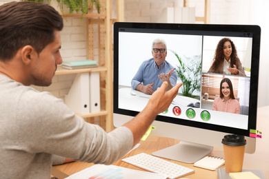 Image of Man having video chat with colleagues at table in office. Team work  