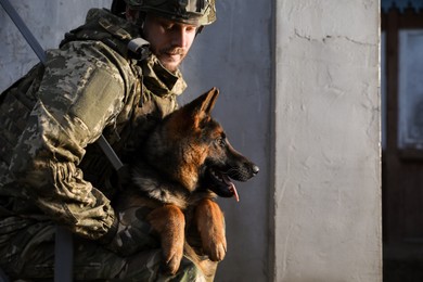 Ukrainian soldier with German shepherd dog outdoors. Space for text