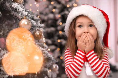 Photo of Surprised child near Christmas tree at home. Space for text