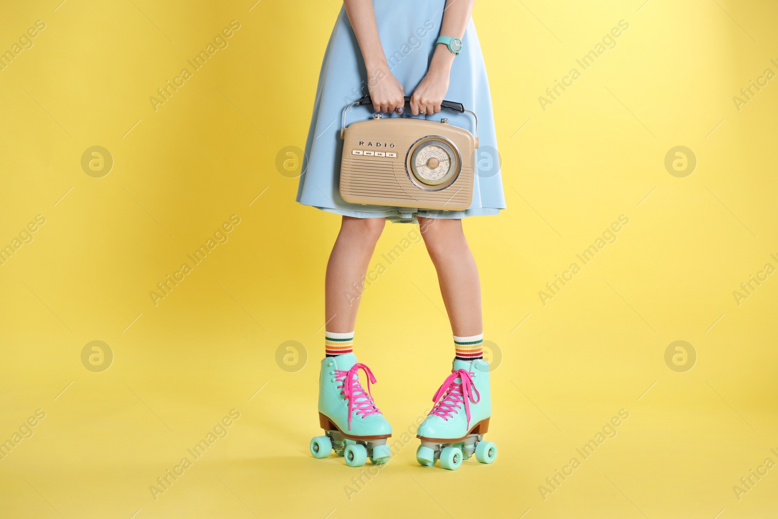 Photo of Young woman with roller skates and retro radio on color background, closeup