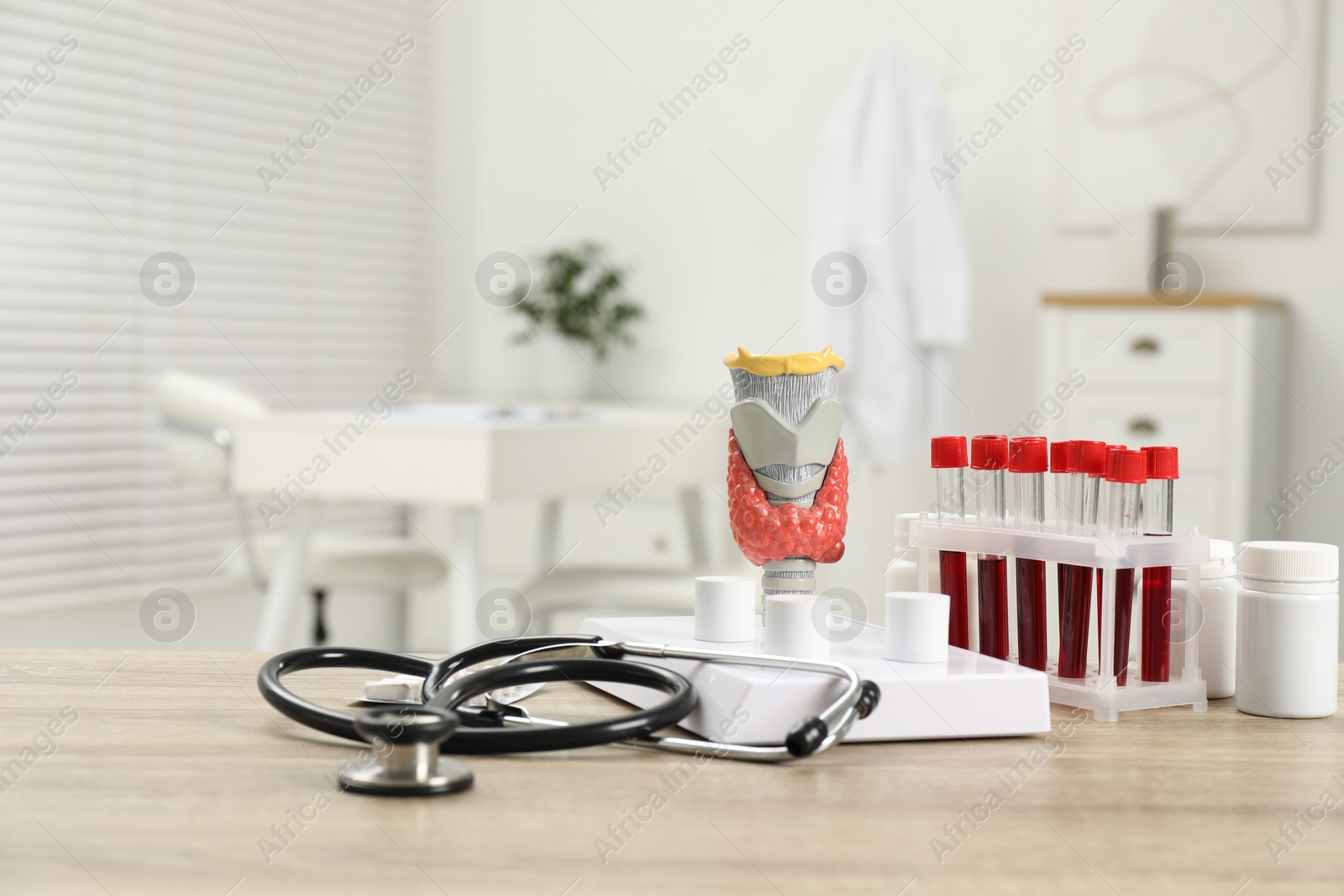 Photo of Endocrinology. Stethoscope, model of thyroid gland and blood samples in test tubes on table indoors