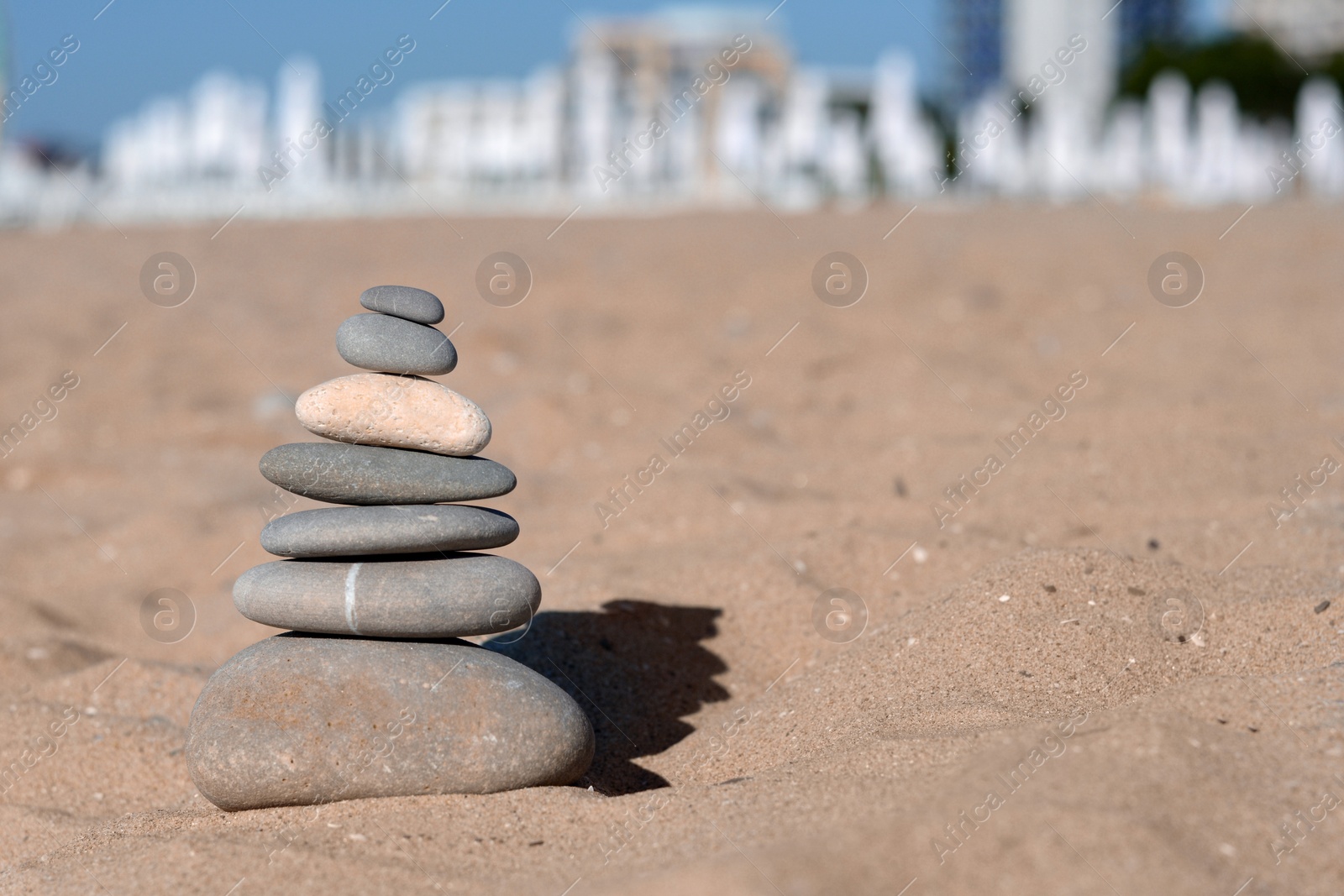 Photo of Stack of stones on sandy beach, space for text