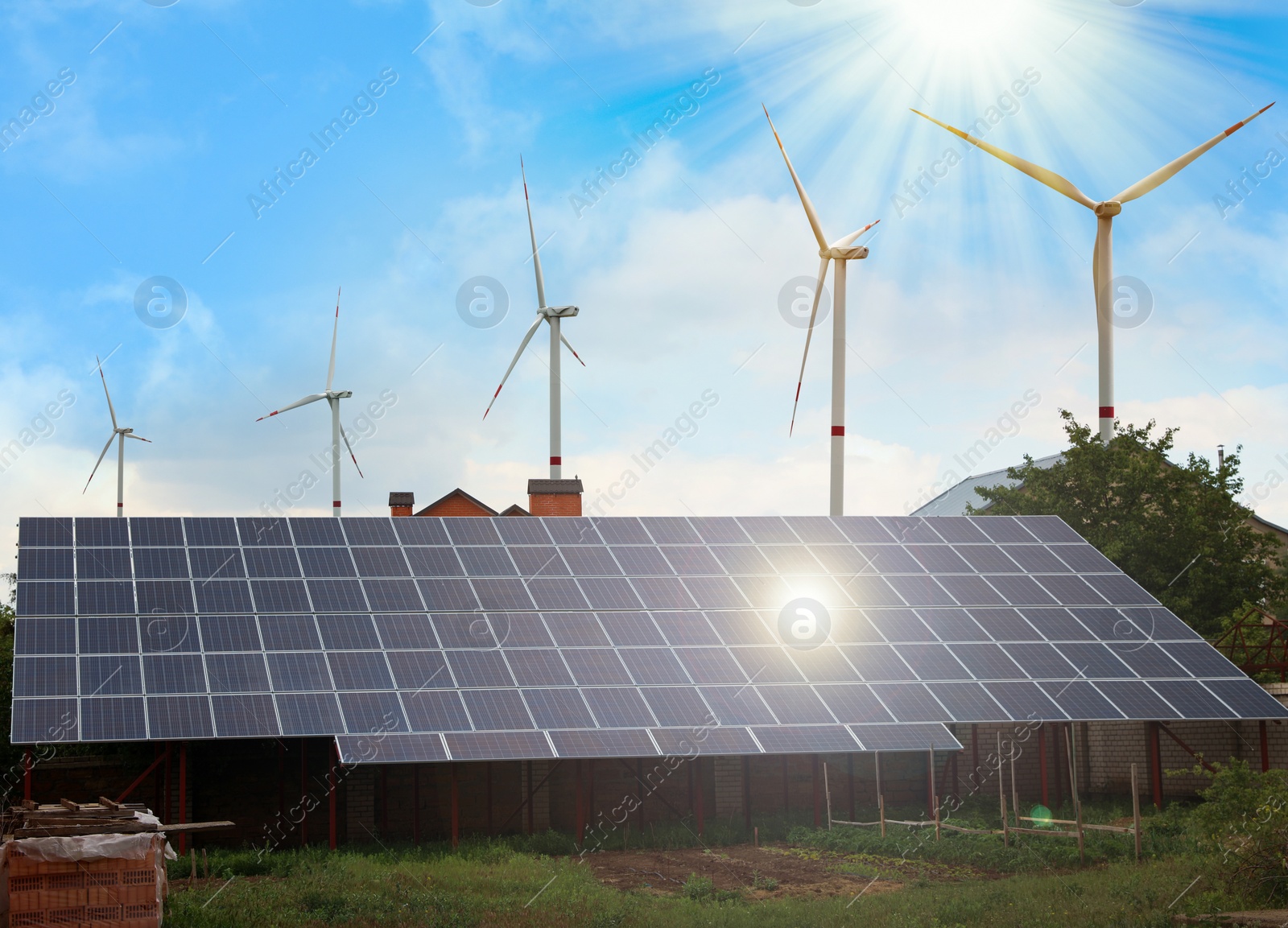 Image of Wind turbines near house with installed solar panels on roof. Alternative energy source