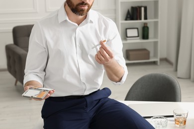 Man with cigarette and case in office, closeup. Space for text