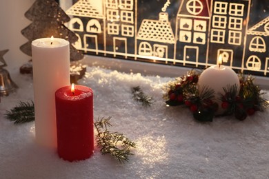 Photo of Beautiful burning candles with Christmas decor near window, space for text