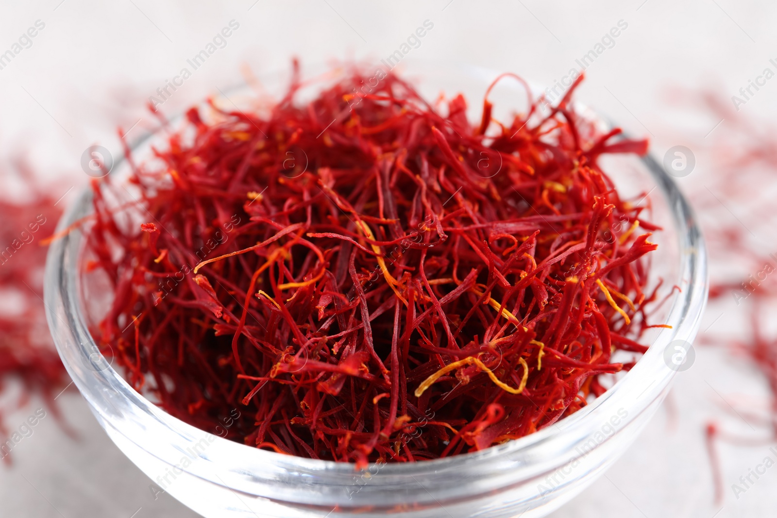 Photo of Dried saffron in glass bowl on table, closeup