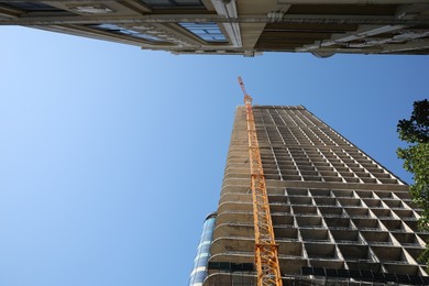 Modern unfinished multistory building against blue sky, low angle view